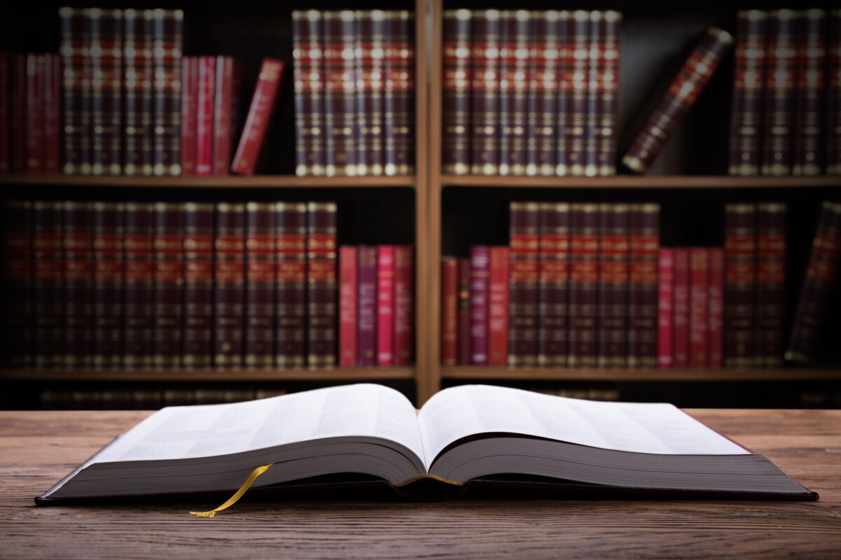 Close-up Of An Open Law Book On Wooden Desk In Courtroom.